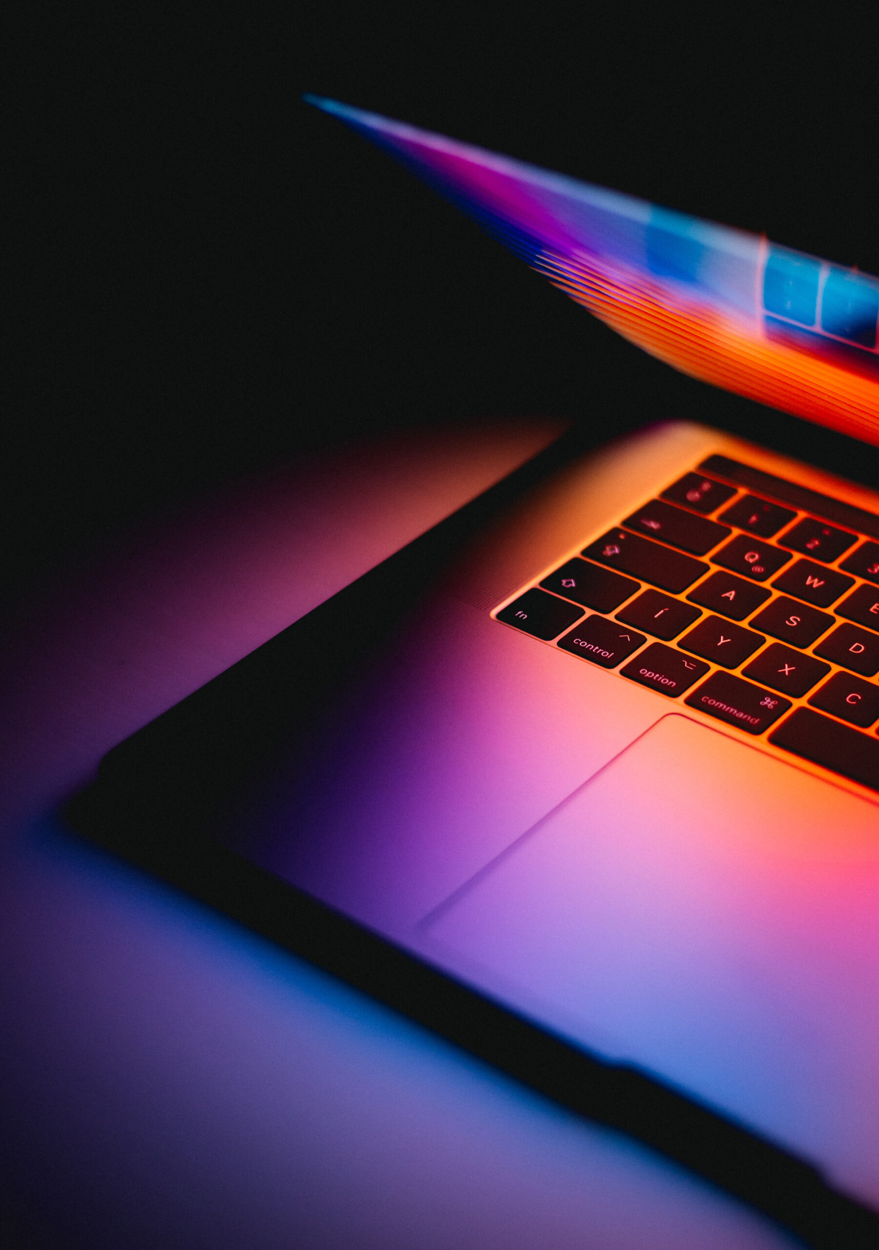 A laptop computer, partially open, with dark dramatic lighting